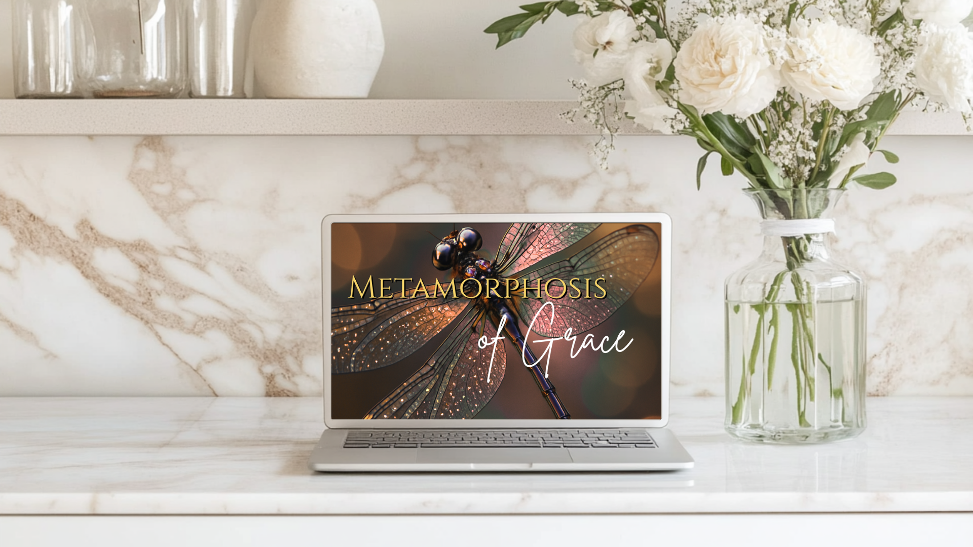 Laptop on a marble surface with a floral arrangement and decorative items.